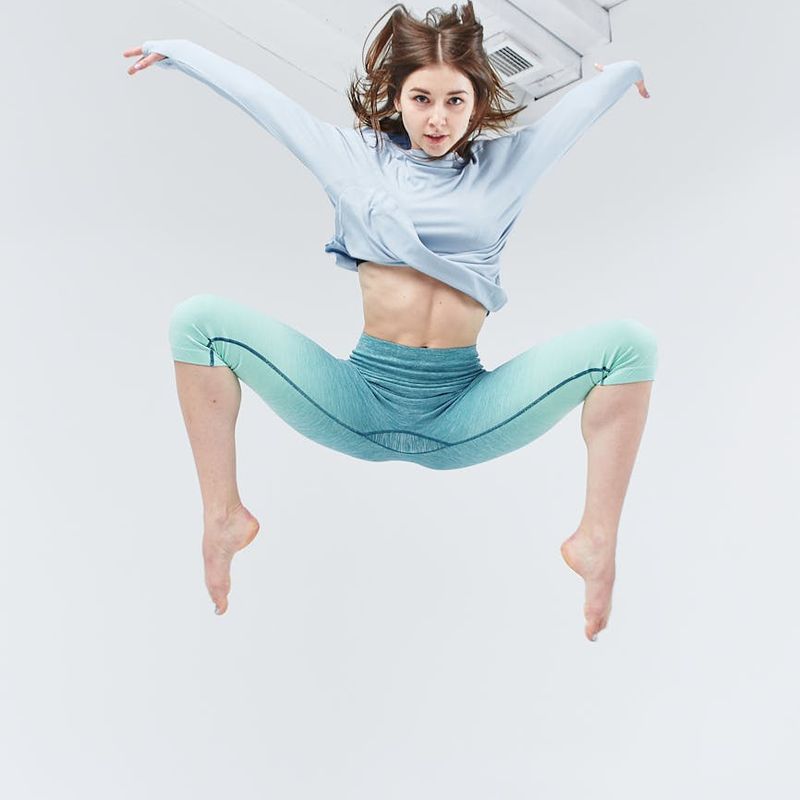 Man in mid-motion during a dynamic stretch in a spacious studio.